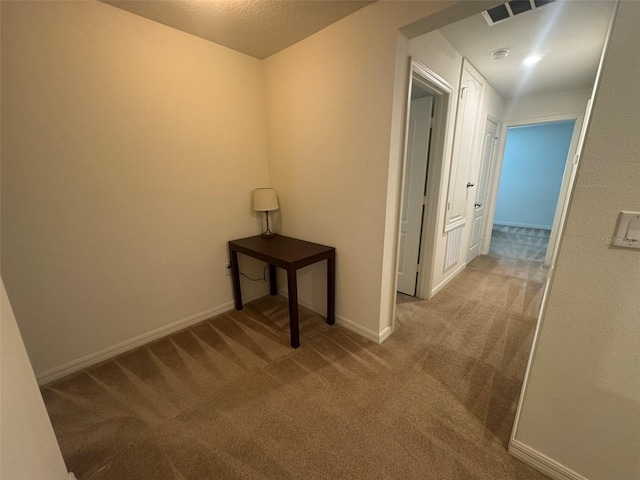 hall with light carpet and a textured ceiling