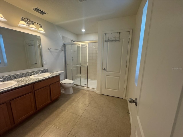 bathroom with vanity, toilet, a shower with shower door, and tile patterned flooring