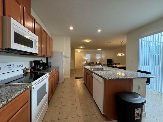 kitchen featuring sink, white appliances, a center island with sink, light tile patterned flooring, and decorative light fixtures