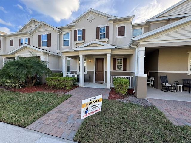 townhome / multi-family property featuring a front yard and covered porch