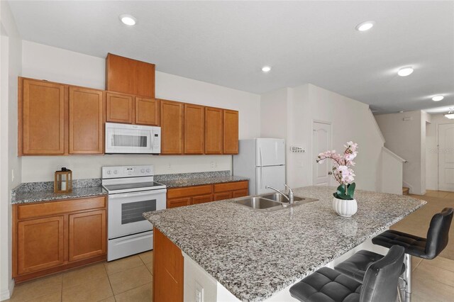 13731 Bravante Aly, Windermere, FL 34786 - kitchen featuring white appliances, a sink, light tile patterned floors, a breakfast bar, and a kitchen island with sink
