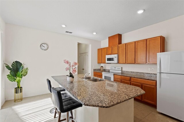 13731 Bravante Aly, Windermere, FL 34786 - kitchen with white appliances, light tile patterned flooring, a kitchen bar, a sink, and a center island with sink