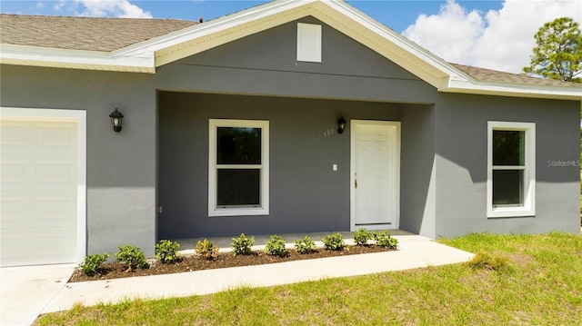 property entrance with a garage and a lawn