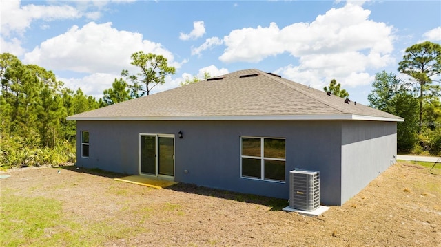 back of property with central AC unit and a lawn