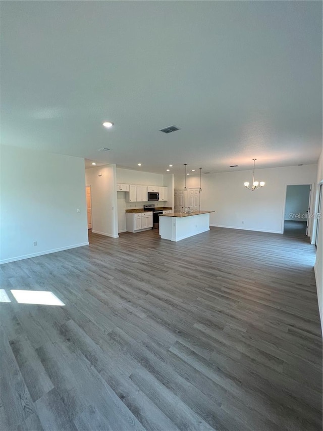 unfurnished living room with an inviting chandelier and hardwood / wood-style flooring