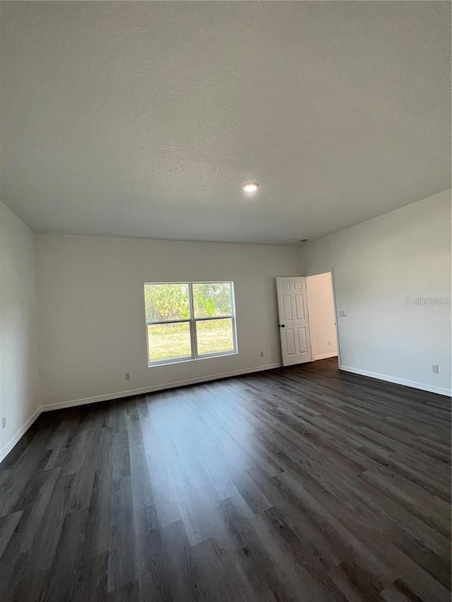 unfurnished room featuring dark wood-type flooring and a textured ceiling