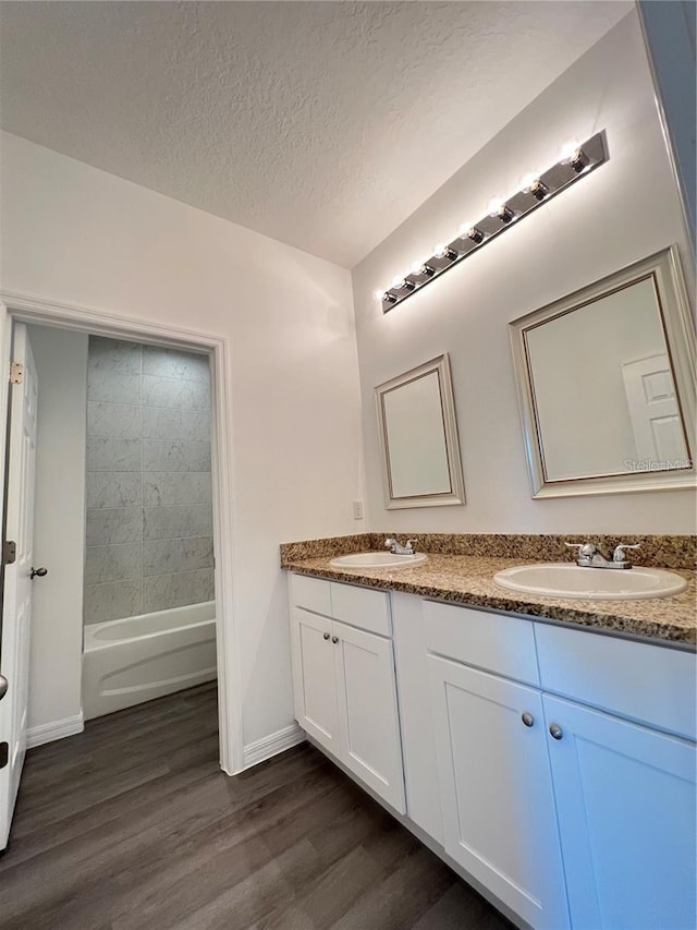 bathroom featuring a textured ceiling, tiled shower / bath combo, hardwood / wood-style flooring, and vanity