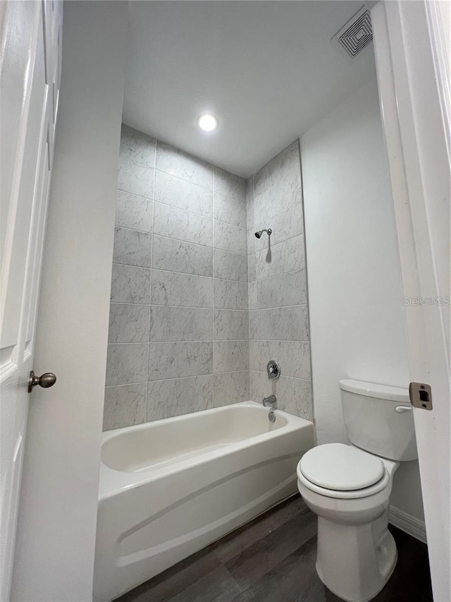 bathroom with toilet, tiled shower / bath combo, and wood-type flooring