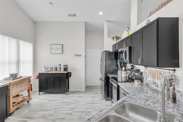 kitchen featuring light stone countertops, appliances with stainless steel finishes, and sink