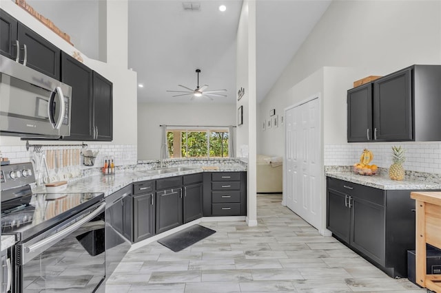 kitchen featuring light stone countertops, backsplash, appliances with stainless steel finishes, and sink