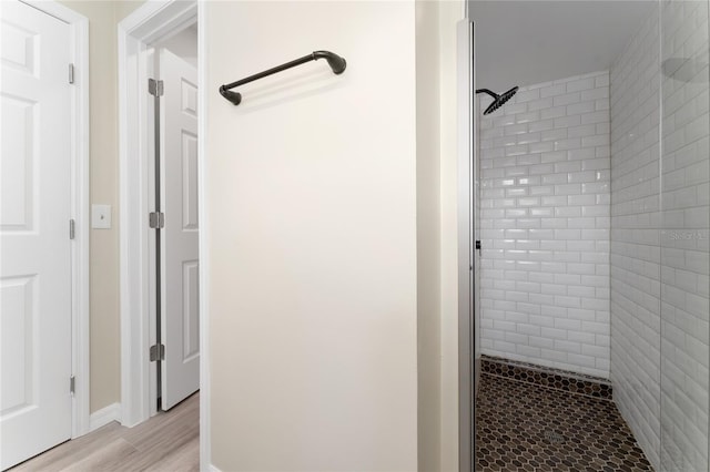 bathroom featuring wood-type flooring and tiled shower