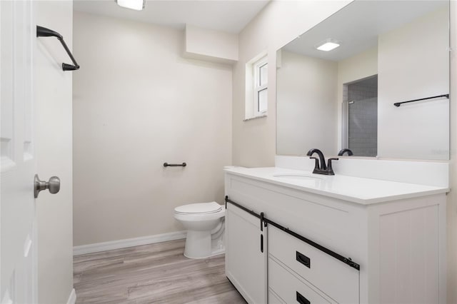 bathroom with toilet, hardwood / wood-style floors, and vanity