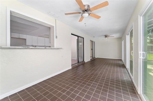 unfurnished sunroom with ceiling fan