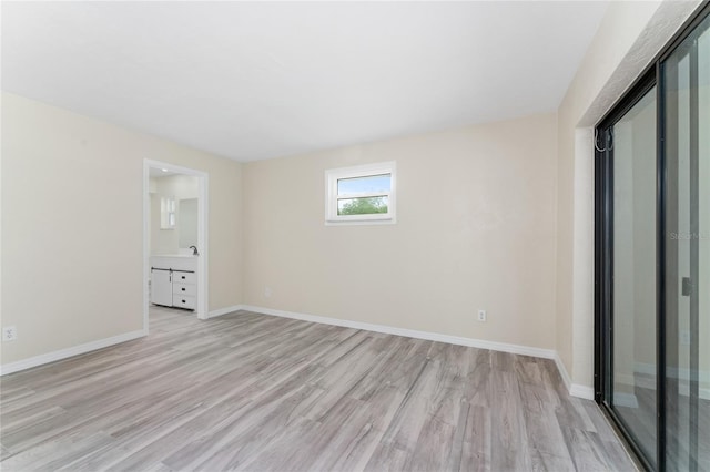 unfurnished bedroom featuring sink, connected bathroom, and light hardwood / wood-style flooring