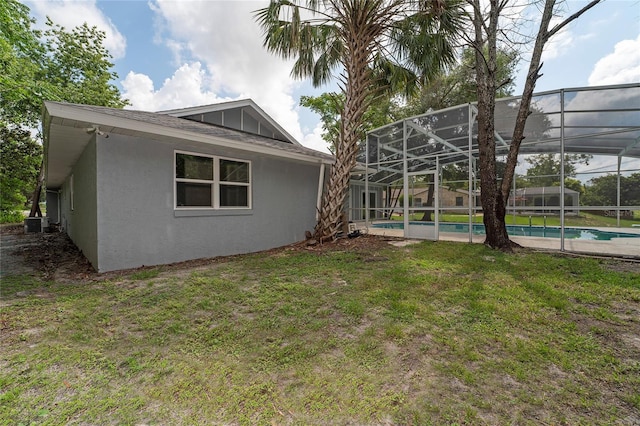 rear view of property featuring a lanai, a yard, and central AC