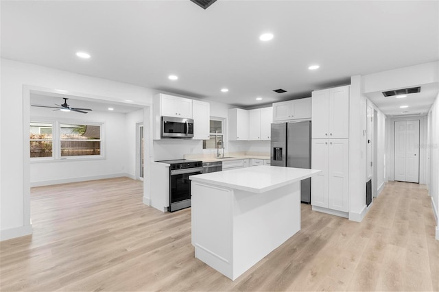 kitchen with sink, white cabinetry, appliances with stainless steel finishes, and a center island