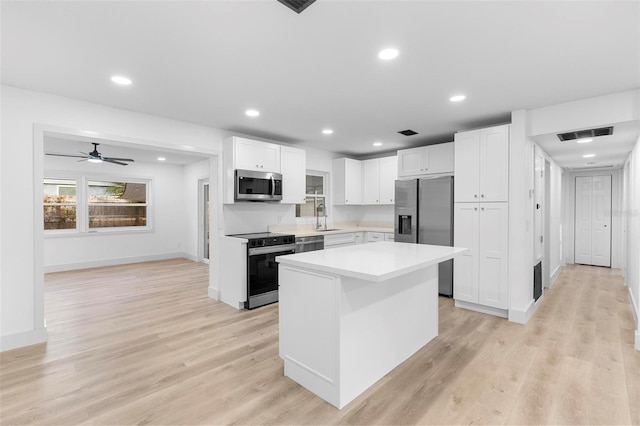 kitchen with stainless steel appliances, light countertops, visible vents, a sink, and white cabinetry