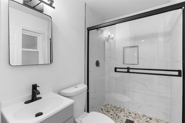 bathroom featuring toilet, vanity, and a marble finish shower