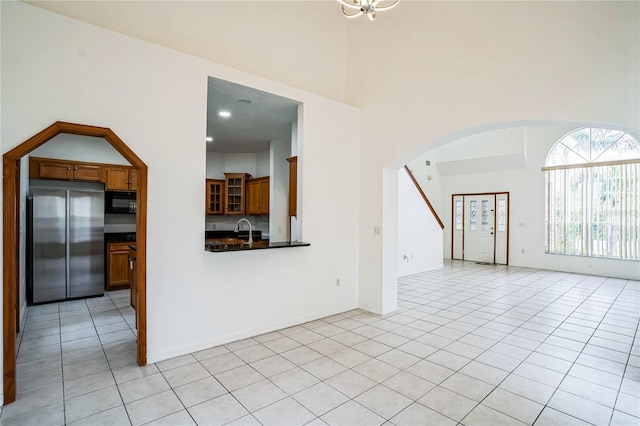 unfurnished living room featuring light tile patterned floors, sink, and a chandelier