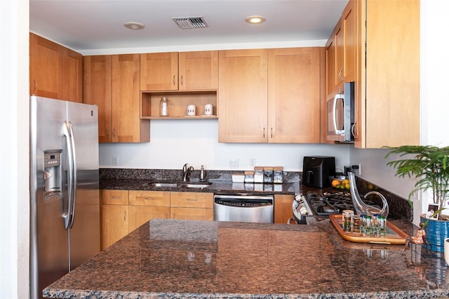 kitchen featuring sink, stainless steel appliances, and dark stone countertops