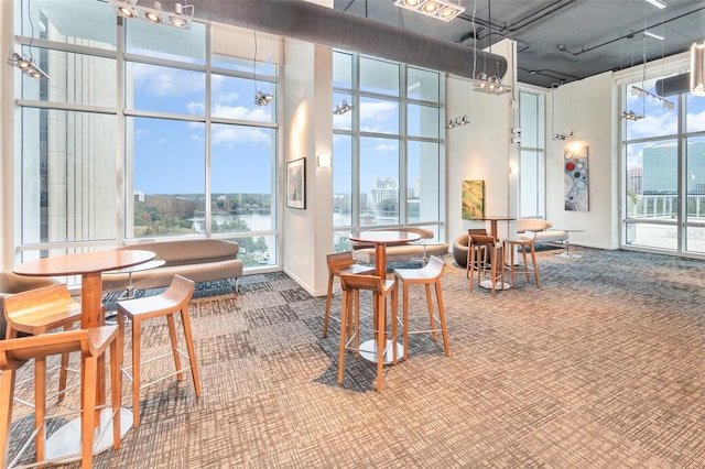 interior space featuring floor to ceiling windows, carpet, a water view, and a towering ceiling