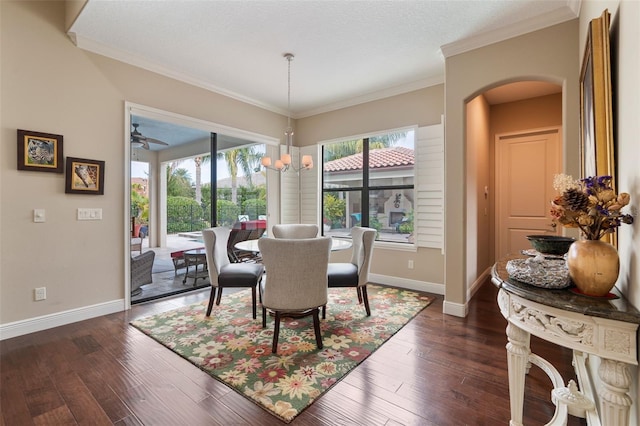 dining area featuring dark wood-type flooring, crown molding, and ceiling fan with notable chandelier