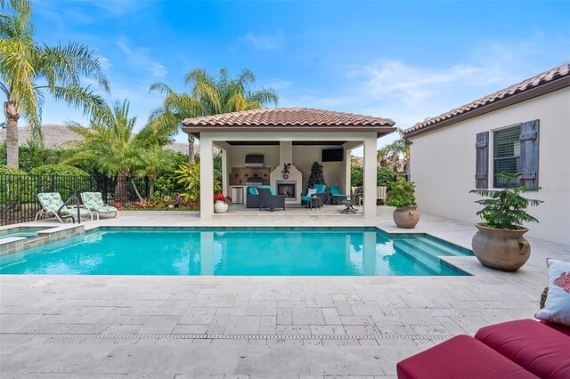 view of pool featuring an in ground hot tub, a gazebo, an outdoor living space with a fireplace, and a patio