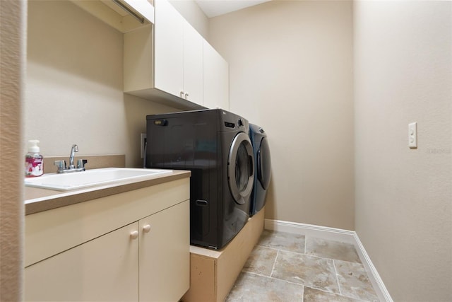 clothes washing area with sink, washer and dryer, and cabinets