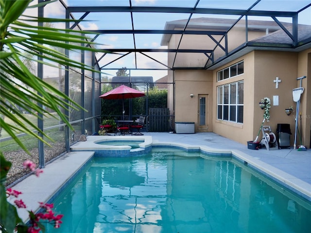 view of pool featuring an in ground hot tub, a patio area, and glass enclosure