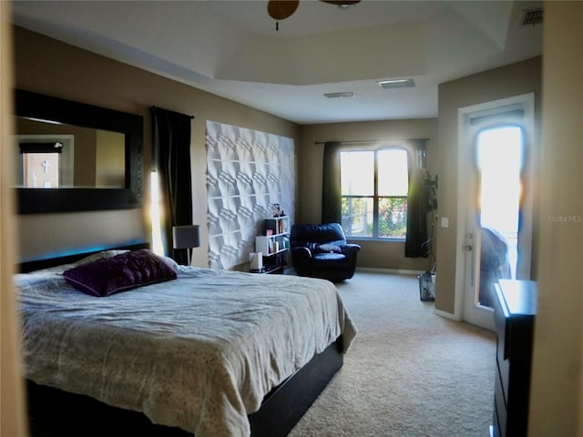 bedroom featuring light colored carpet, ceiling fan, and a tray ceiling