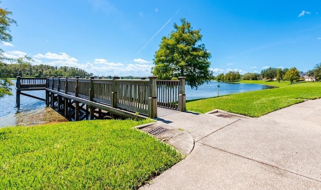 view of dock with a water view and a yard