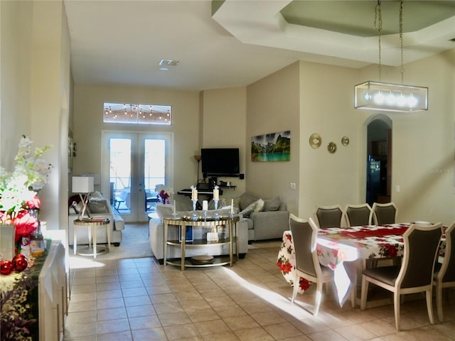 tiled dining room with a raised ceiling and french doors