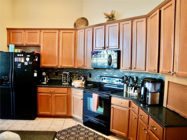 kitchen featuring tasteful backsplash, light tile patterned flooring, dark stone counters, and black appliances