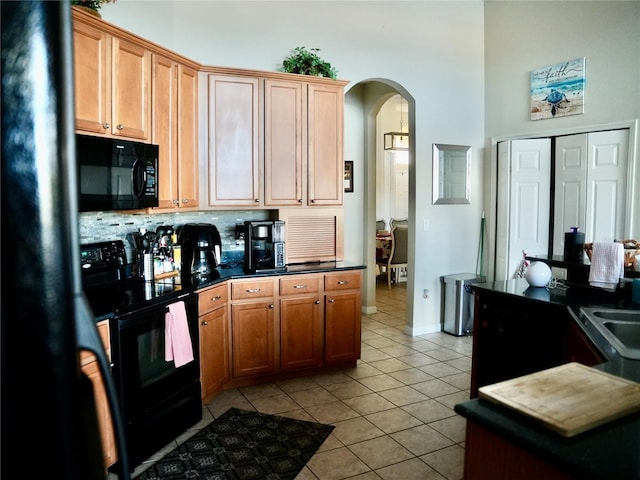 kitchen featuring sink, light tile patterned floors, decorative backsplash, and black appliances