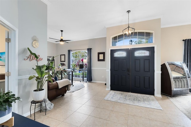 tiled entrance foyer featuring ceiling fan with notable chandelier and crown molding