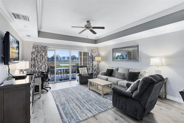 living room with crown molding, ceiling fan, a tray ceiling, and light wood-type flooring