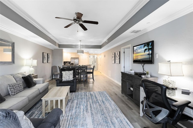 living room with hardwood / wood-style floors, ornamental molding, a raised ceiling, and ceiling fan