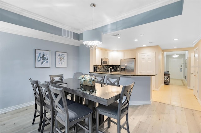 dining space with crown molding, light hardwood / wood-style floors, and a chandelier