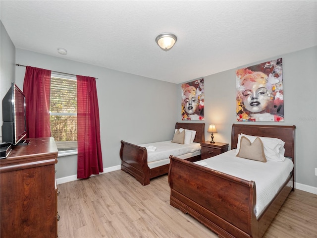 bedroom featuring a textured ceiling and light hardwood / wood-style flooring