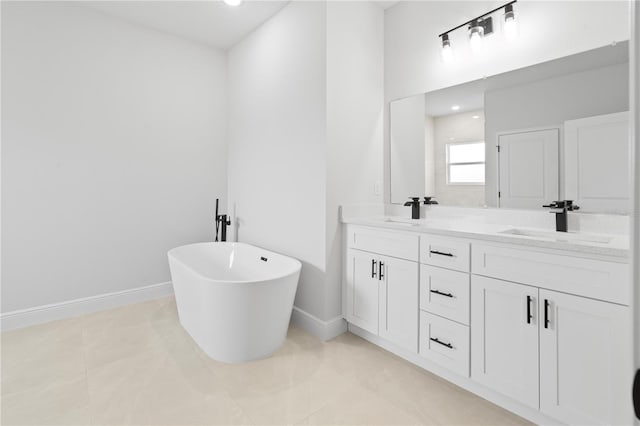 bathroom featuring double vanity, a freestanding tub, a sink, and baseboards