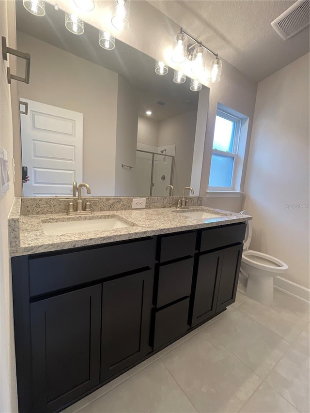 bathroom featuring toilet, vanity, tile patterned flooring, a textured ceiling, and a shower with door