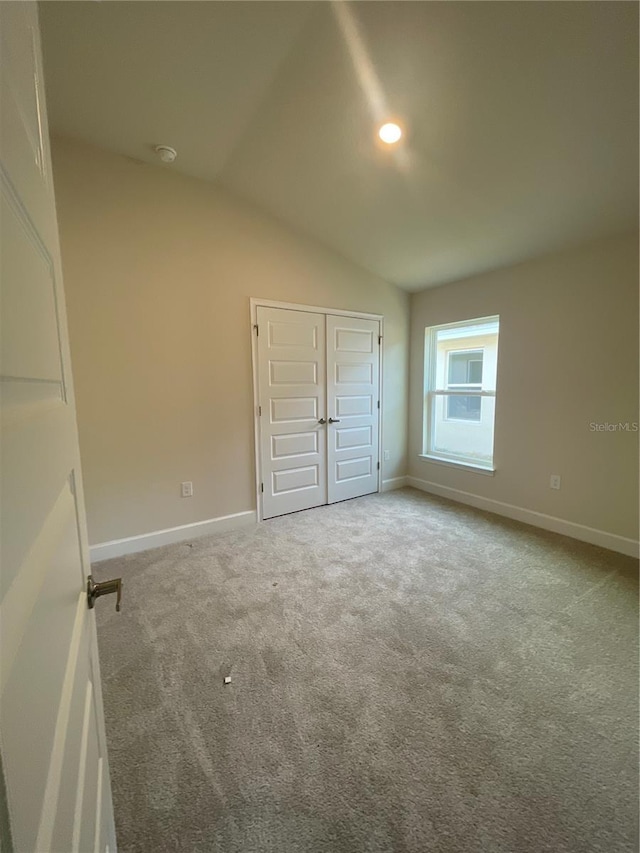 unfurnished bedroom with carpet and vaulted ceiling