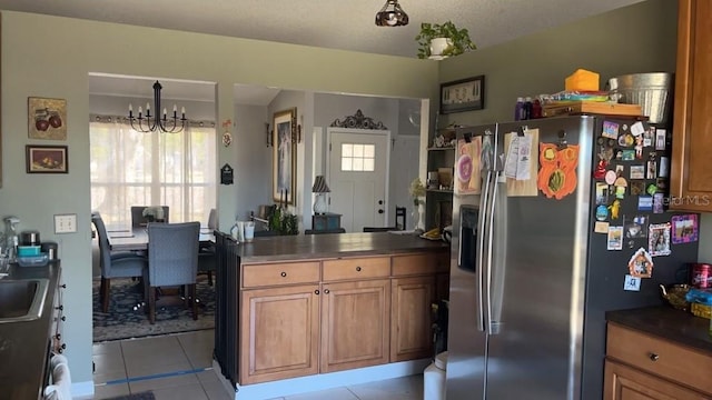 kitchen with a textured ceiling, light tile patterned floors, stainless steel fridge, a notable chandelier, and pendant lighting