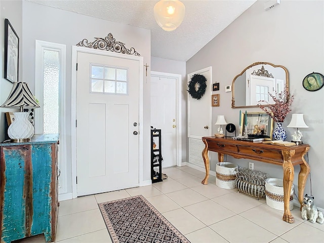 tiled entryway with vaulted ceiling and a textured ceiling