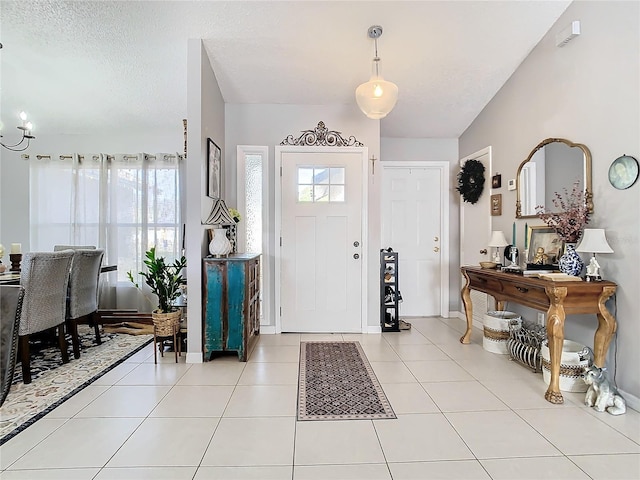 foyer entrance with lofted ceiling, a healthy amount of sunlight, light tile patterned floors, and a textured ceiling