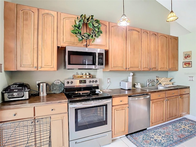 kitchen with vaulted ceiling, appliances with stainless steel finishes, sink, and pendant lighting