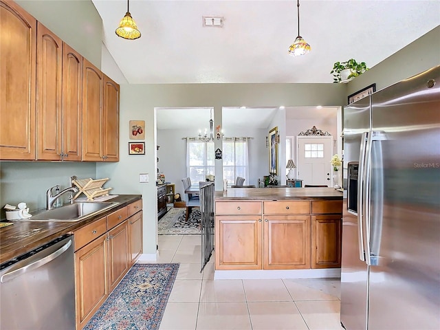 kitchen with stainless steel appliances, sink, pendant lighting, and light tile patterned floors