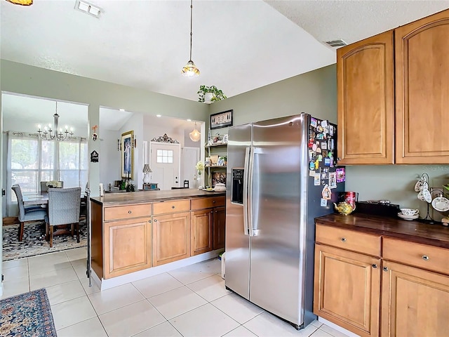 kitchen featuring pendant lighting, light tile patterned floors, an inviting chandelier, stainless steel refrigerator with ice dispenser, and kitchen peninsula