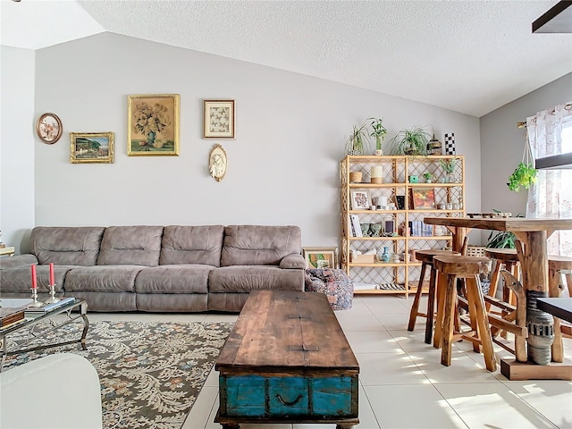 living room featuring lofted ceiling, light tile patterned floors, and a textured ceiling