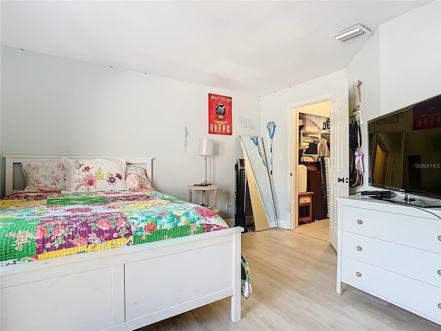 bedroom featuring a spacious closet and light hardwood / wood-style flooring